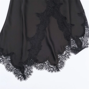 Detail of elegant black satin slip dress showing intricate wavy lace hem craftsmanship