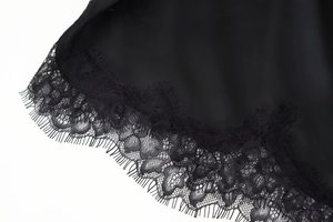 Gros plan sur le tissu en satin noir soyeux avec des détails en dentelle délicate