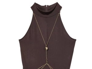 Detail of high neck halter dress with golden chain decoration on smooth brown fabric