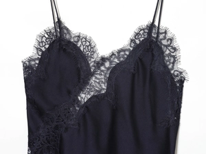 Detail of elegant black satin top featuring intricate eyelash lace and deep V-neckline
