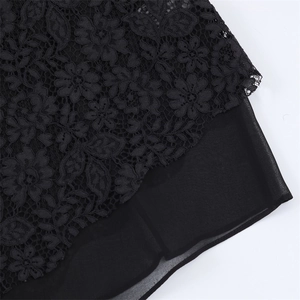 Vue macro détaillée de dentelle florale noire superposée sur du tissu mousseline