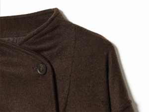 Detail of dark brown wool jacket featuring high-quality fabric texture and button closure