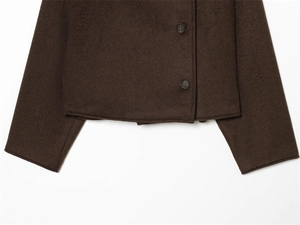 Detail of dark brown wool jacket hem with neat stitching and black round buttons