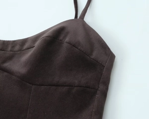 Close-up of dark brown suede-like fabric showing detailed stitching and panel construction