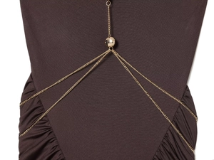 Detail shot of a polished gold sphere body chain accessory on a dark textured dress