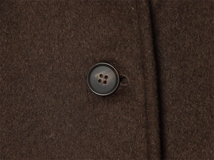 Close-up of wool fabric texture and round brown button on a winter jacket coat
