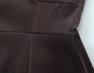 Detailed macro view of high-quality stitching on dark brown velvet fabric dress