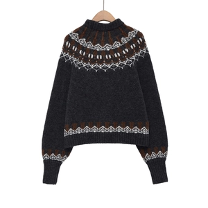 Detailed view of Fair Isle patterns on dark grey knit sweater with ribbed cuffs