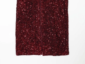 Detailed close-up of wine red sequin dress hem showing slit design and metallic texture