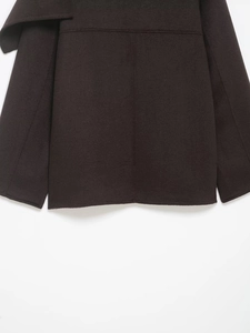 Detail of dark brown wool coat hem and sleeve showing premium thick fabric texture