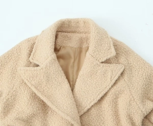 Close-up of light beige faux shearling coat collar with smooth lining and grainy texture
