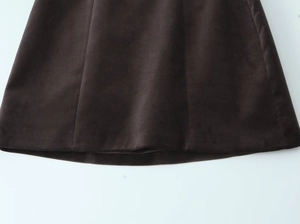 Detail shot of a dark brown velvet A-line skirt featuring fine vertical stitching seams