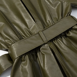 Detailed view of the olive green leather jacket featuring a wide belt and pleating details