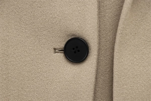 Close-up detail of a black button and textured wool fabric on a khaki winter coat