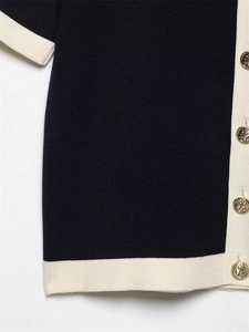 Detail of navy knitwear featuring golden anchor buttons and cream contrast trim