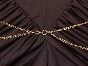 Detailed macro view of golden metal chain accessory and lobster clasp on dark brown fabric