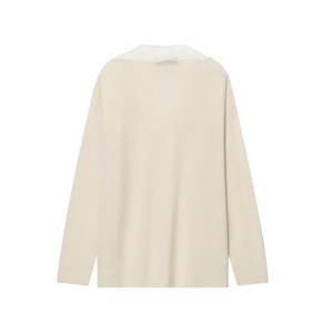 Detail of elegant lace trim and frayed fringe on the back neckline of a cream knit sweater