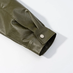 Detail shot of olive green leather jacket cuff with silver metal snap button and texture