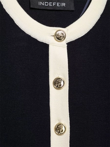 Detail of navy knit cardigan featuring gold anchor buttons and ivory contrast trim