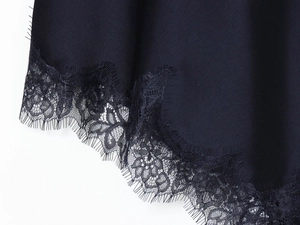 Detailed macro view of delicate black eyelash lace trim on a silky navy blue dress hem