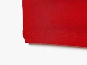 Détail macro de la couture double aiguille sur l'ourlet de la robe en maille rouge