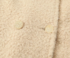 Close-up of beige faux wool texture and golden textured buttons on long winter coat