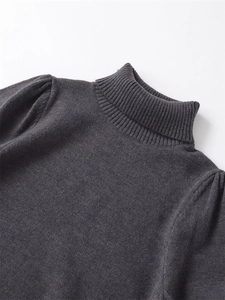 Detail shot of the ribbed high-neck and puffed shoulders on a dark grey knit sweater