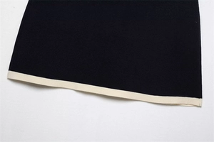 Close-up of knit fabric texture with contrasting white hem on a dark sweater