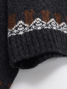 Detailed macro shot of dark grey knitwear with brown geometric mountain pattern texture