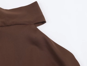 Detailed view of dark brown satin top featuring asymmetrical neckline and fine twill texture