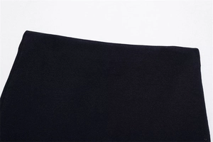 Detailed macro view of the smooth black knit fabric texture and hemline of the women set