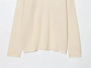 Detailed macro view of high-quality knit texture on minimalist cream long-sleeve sweater