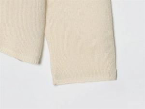 Close-up of cream white knit sweater cuff showing detailed fine stitch texture and fabric