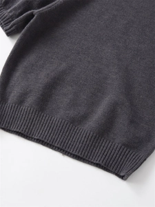Detail of dark grey knit sweater showing the ribbed hem texture and fine fabric finish
