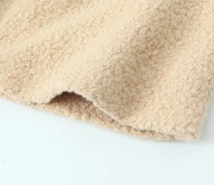 Detailed macro view of the cream-colored faux shearling wool fabric with neat edge stitching