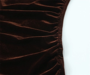 Detail view of dark brown velvet fabric with soft sheen and elegant ruched texture design