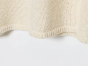 Close-up detail of the ribbed hem on a soft cream lace knit sweater for women
