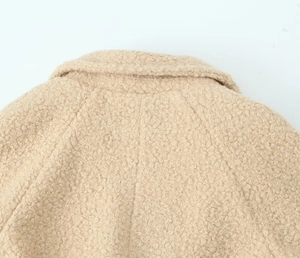 Close-up of beige fleece coat showing textured faux shearling fabric and back collar detail