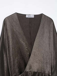 Macro shot of V-neckline detail on a glossy satin dress with elegant pleated fabric texture