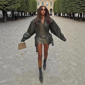 Women's olive green leather biker jacket with belt in a stylish autumn street outfit