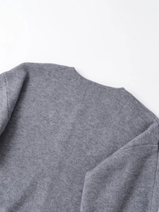 Detailed close-up of a grey knit sweater featuring ribbed neckline and flat-stitch texture