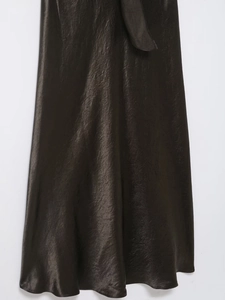Detail of elegant satin maxi skirt in deep brown with waist tie and smooth silk-like texture