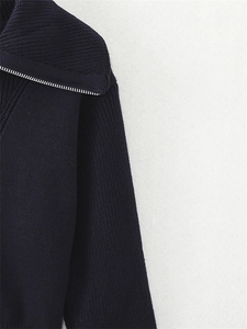 Dettaglio della cerniera argentata e della maglia spessa blu navy su questo maglione