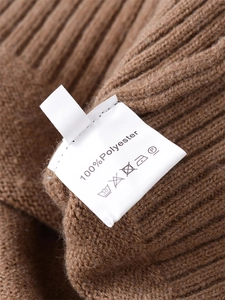 Detail view of the washing care label on a brown loose-fit ribbed knit polyester sweater
