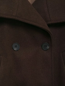 Vue macro du tissu en laine marron foncé et des boutons classiques à quatre trous