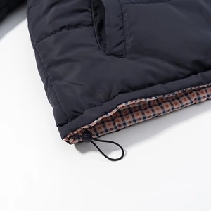 Detail of black puffer jacket hem with plaid lining and adjustable elastic drawstring