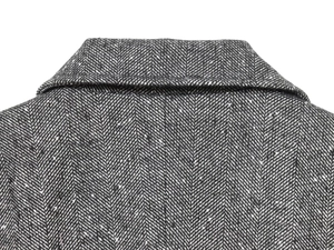 Detailed close-up of grey herringbone wool fabric texture on a women blazer lapel