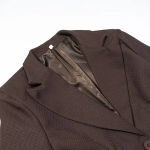 Detail of the notched lapel and woven texture on a dark brown tailored blazer jacket