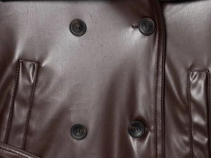 Close-up of dark brown faux leather trench coat with double-breasted buttons and pockets