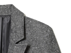 Close-up of grey and white herringbone fabric texture on slim-fit blazer jacket